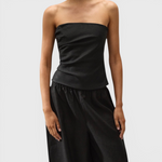 JONES + CO black strapless Alzira top in breezy linen with asymmetric front pleats worn by a model