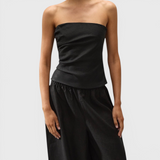 JONES + CO black strapless Alzira top in breezy linen with asymmetric front pleats worn by a model