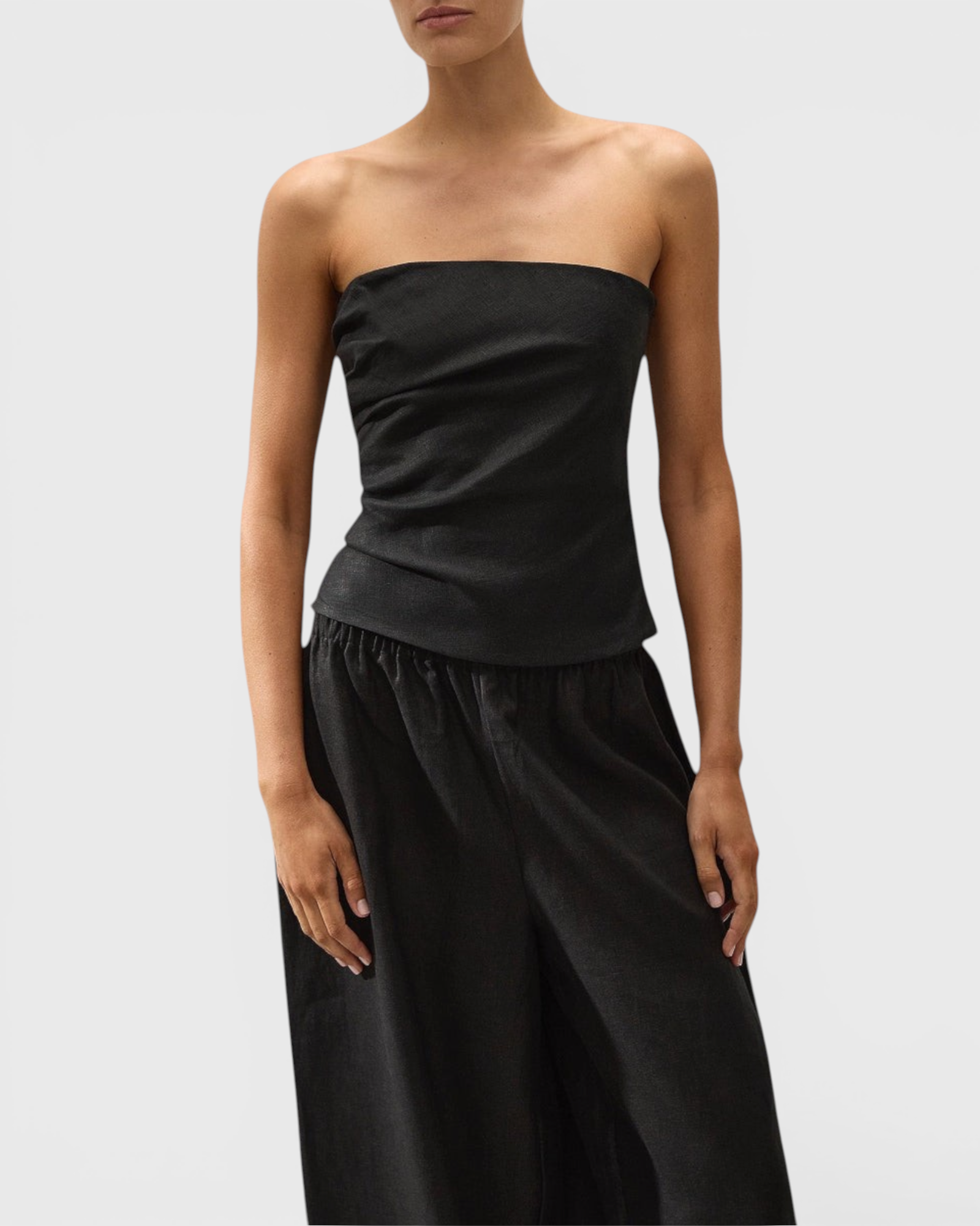 JONES + CO black strapless Alzira top in breezy linen with asymmetric front pleats worn by a model