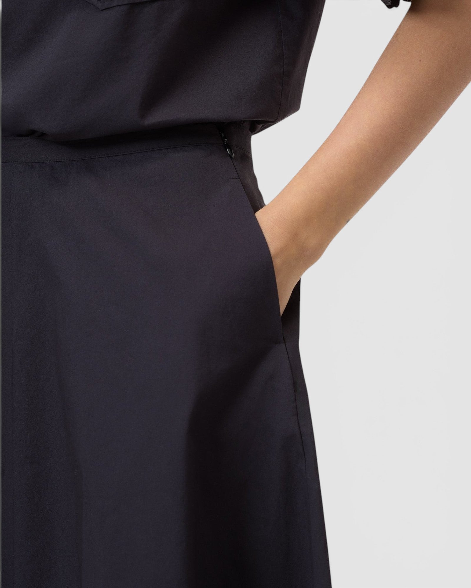 JONES + CO black midi skirt featuring a side pocket and discreet side-seam zip closure.