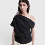JONES + CO black one-shoulder blouse in organic crisp cotton with an asymmetric neckline and draped silhouette.