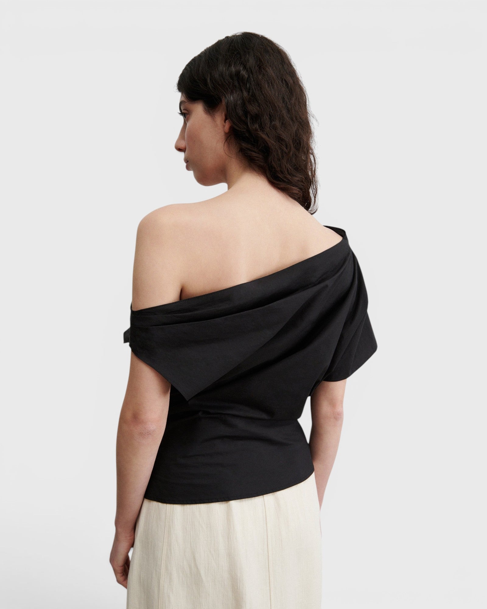 JONES + CO black one-shoulder Mata top in organic crisp cotton with an asymmetric neckline and short sleeve.