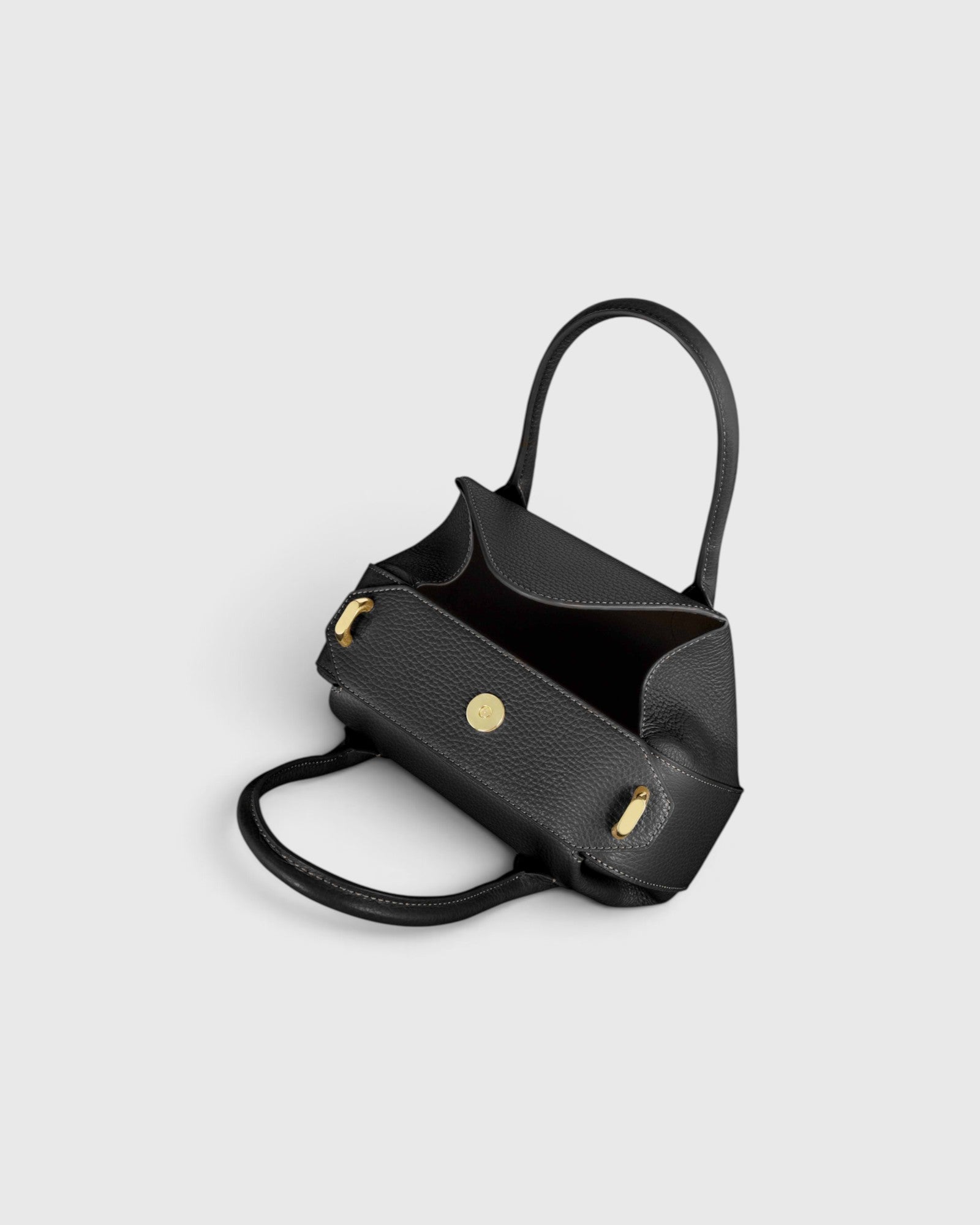 JONES + CO Oyster mini duffle bag in black pebble grained Italian leather with gold-tone hardware and top handles.