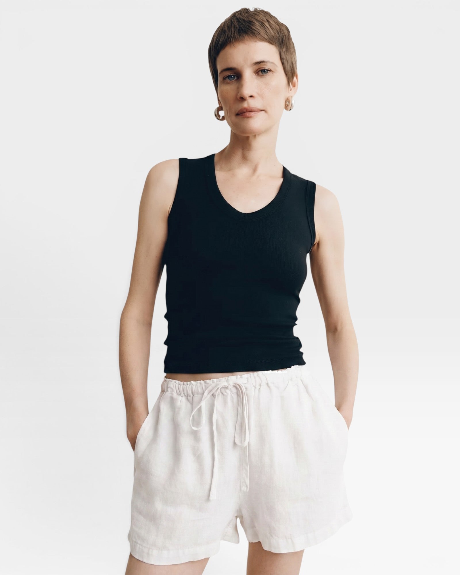 JONES + CO black ribbed knit tank top with a deep scoop neckline, paired with rust linen shorts.