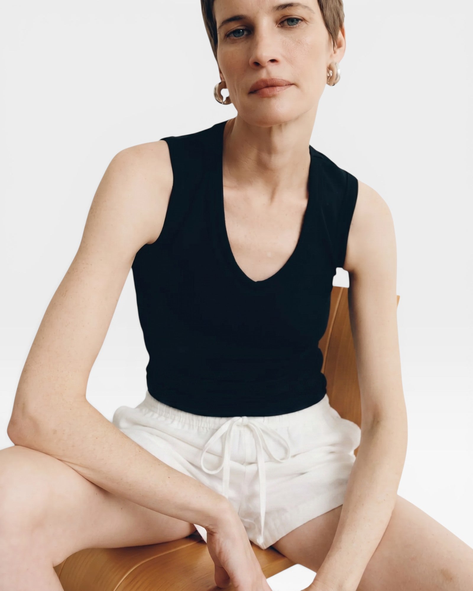 JONES + CO black ribbed knit tank top with deep scoop neck, worn by a model with short hair.