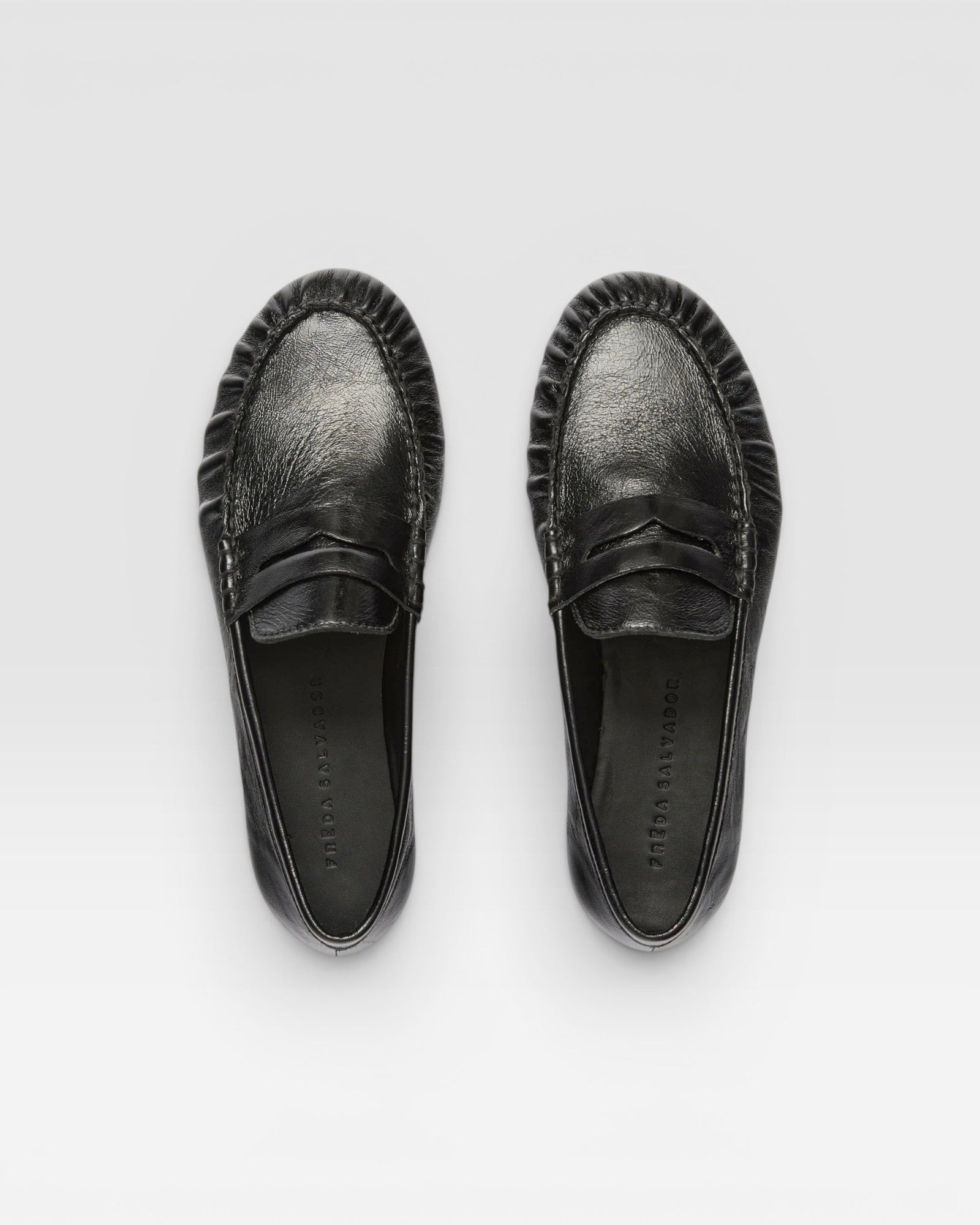 JONES + CO Sydney black crinkle patent leather penny loafers with ruched detailing, top-down view.