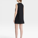JONES + CO black sleeveless mini shift dress with a simple neckline and hem. Model wears sunglasses and sandals.