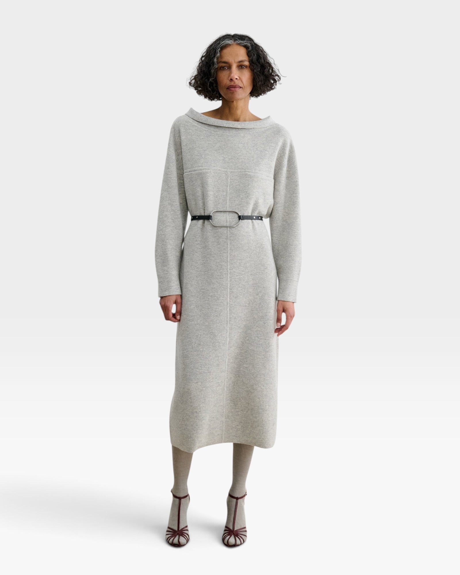 Model wearing JONES + CO black leather Studded Cole Belt with oversized oval buckle over a grey knit midi dress
