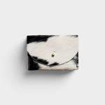 JONES + CO black and white cowhide cardholder with a solid brass fastener, featuring a natural hair-on-hide texture.