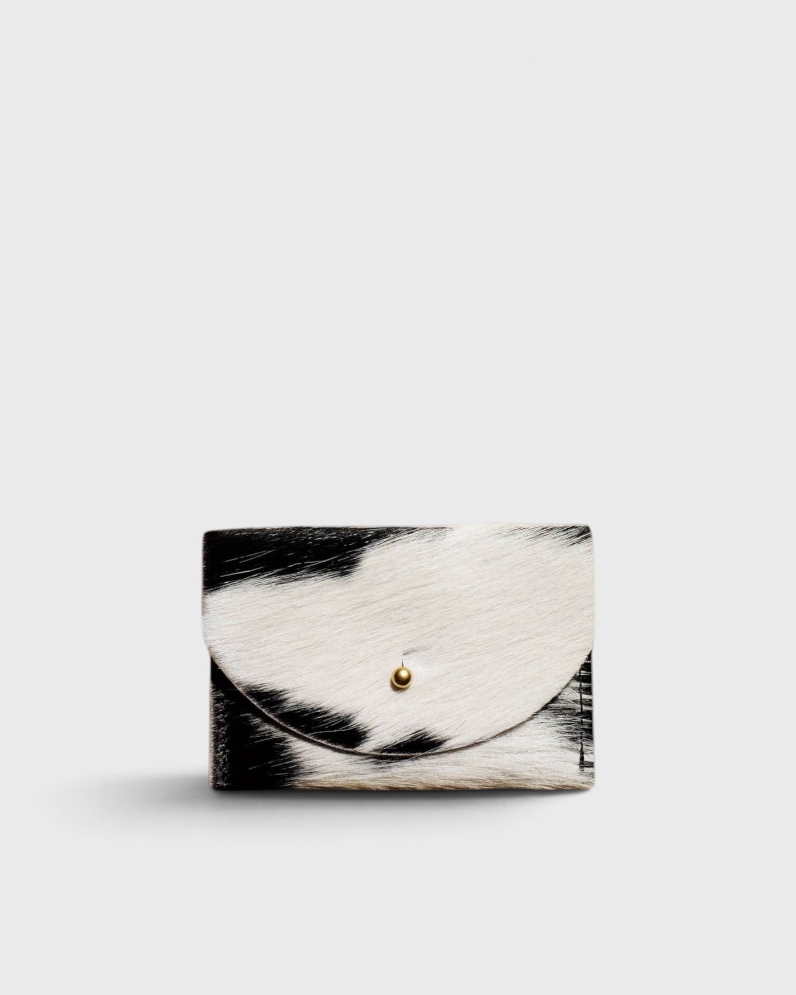 JONES + CO black and white cowhide cardholder with a solid brass fastener, featuring a natural hair-on-hide texture.