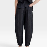 JONES + CO black Lyocell blend balloon-leg trousers with wrinkle finish, elasticated waist, side pockets, and ankle buttons.