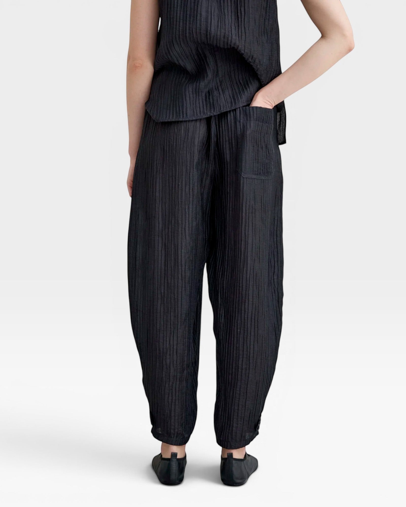 JONES + CO black Lyocell blend balloon-leg trousers with wrinkle finish, elasticated waist, side pockets, and ankle buttons.