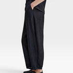 JONES + CO black Lyocell blend wrinkle trousers with balloon legs, elasticated waistband, side pockets, and button ankle details.
