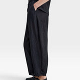 JONES + CO black Lyocell blend wrinkle trousers with balloon legs, elasticated waistband, side pockets, and button ankle details.