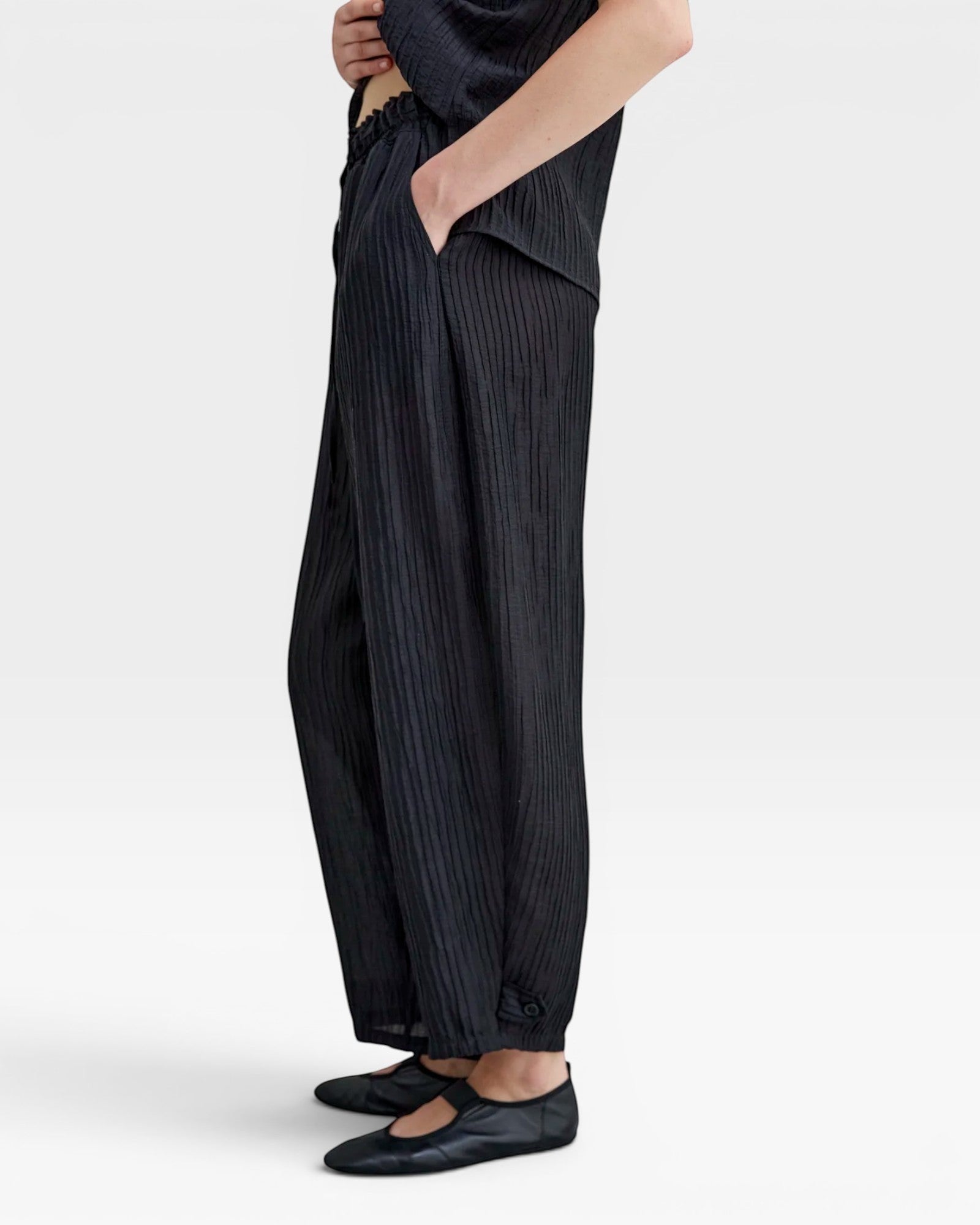 JONES + CO black Lyocell blend wrinkle trousers with balloon legs, elasticated waistband, side pockets, and button ankle details.