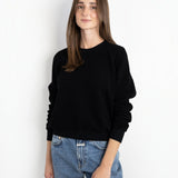 Model wearing a JONES + CO black Ziggy sweatshirt with a shrunken fit and cropped sleeves, paired with blue jeans.