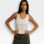 JONES + CO Blondie bright ivory ribbed tank top worn by a woman with hands on hips, styled with olive green pants.