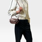 JONES + CO Bon-Bon Cords bag in shiny taupe Italian leather with a pleated design and slim cord shoulder strap.