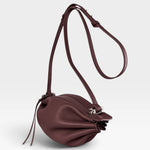 JONES + CO Bon-Bon wine red calf leather shoulder bag with pleated ends, adjustable strap, and silver brass hardware.
