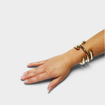 JONES + CO polished brass cuff bracelet worn on a woman's wrist, featuring a modern spiraled design.
