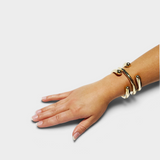 JONES + CO polished brass cuff bracelet worn on a woman's wrist, featuring a modern spiraled design.