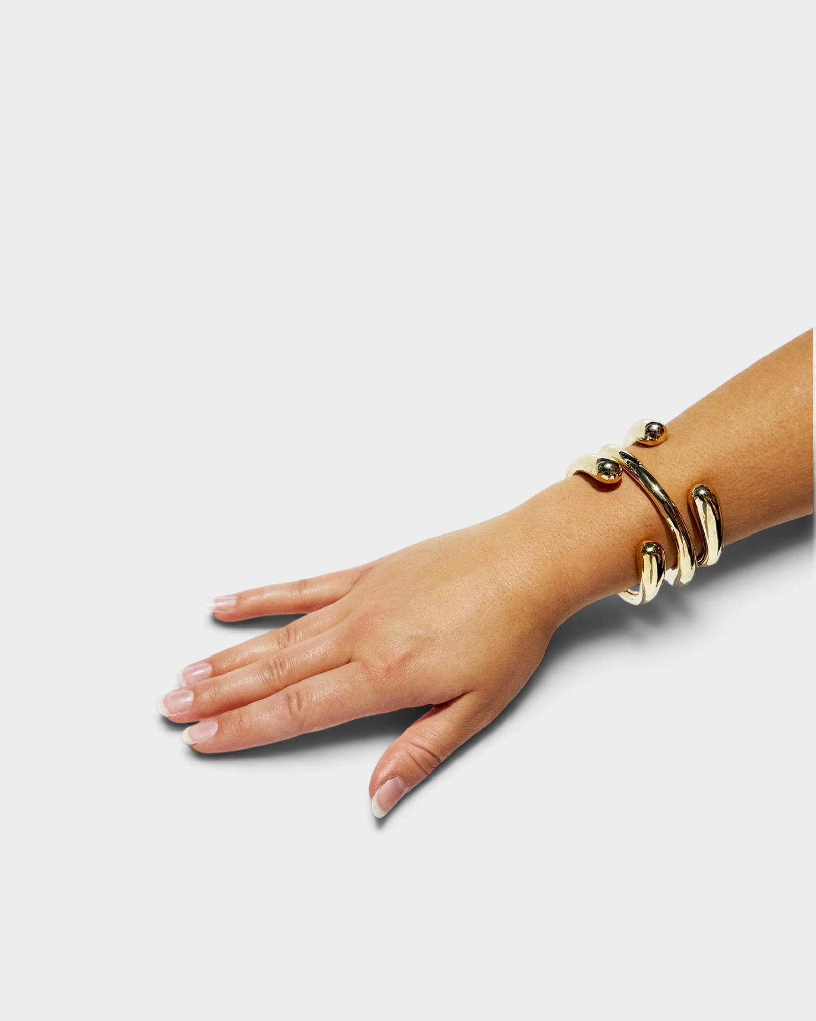 JONES + CO polished brass cuff bracelet worn on a woman's wrist, featuring a modern spiraled design.
