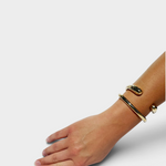 JONES + CO polished brass cuff bracelet worn on a woman's wrist, featuring a minimalist open-ended design.
