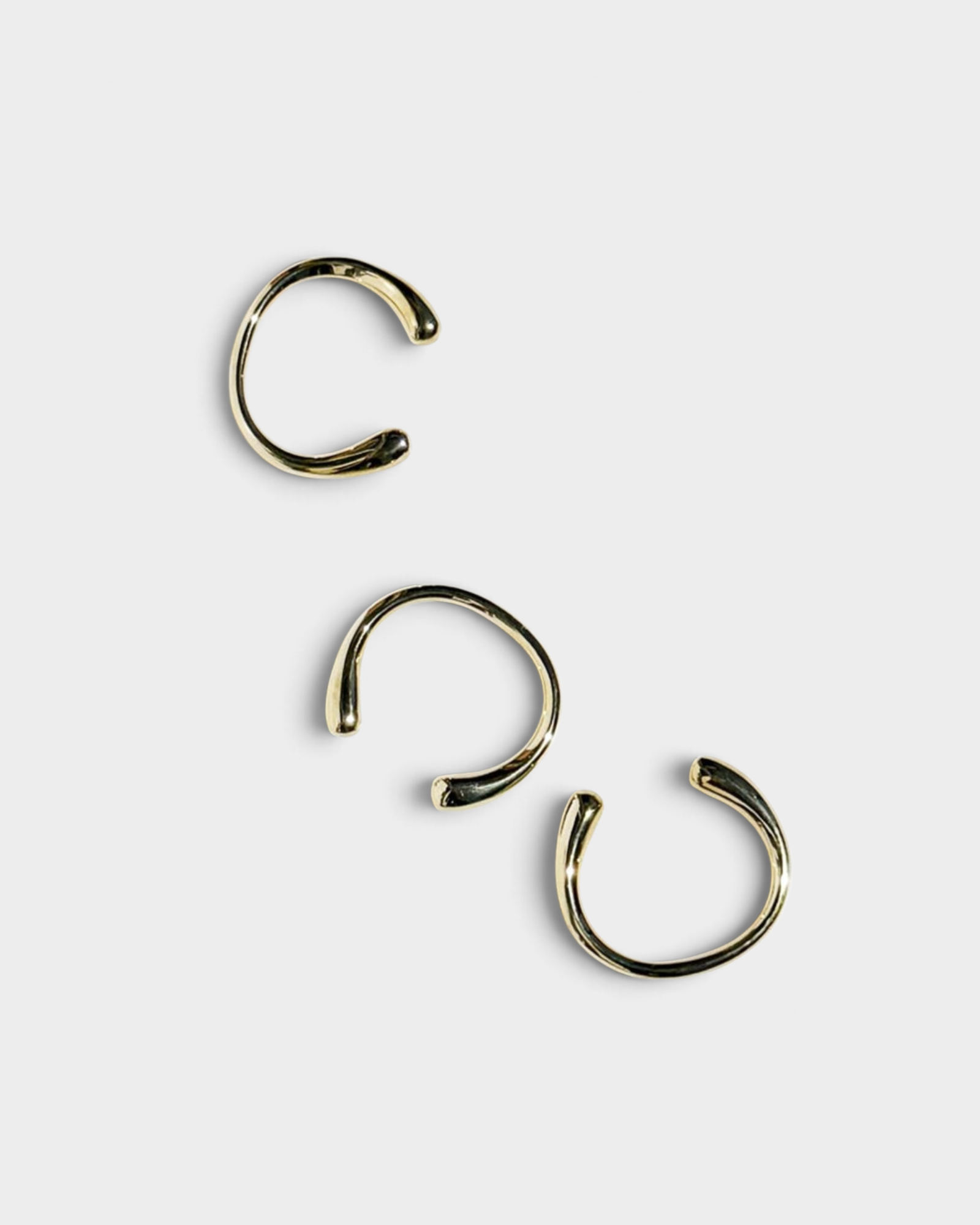JONES + CO set of three minimalist polished brass cuff bracelets with a smooth, open-ended design.