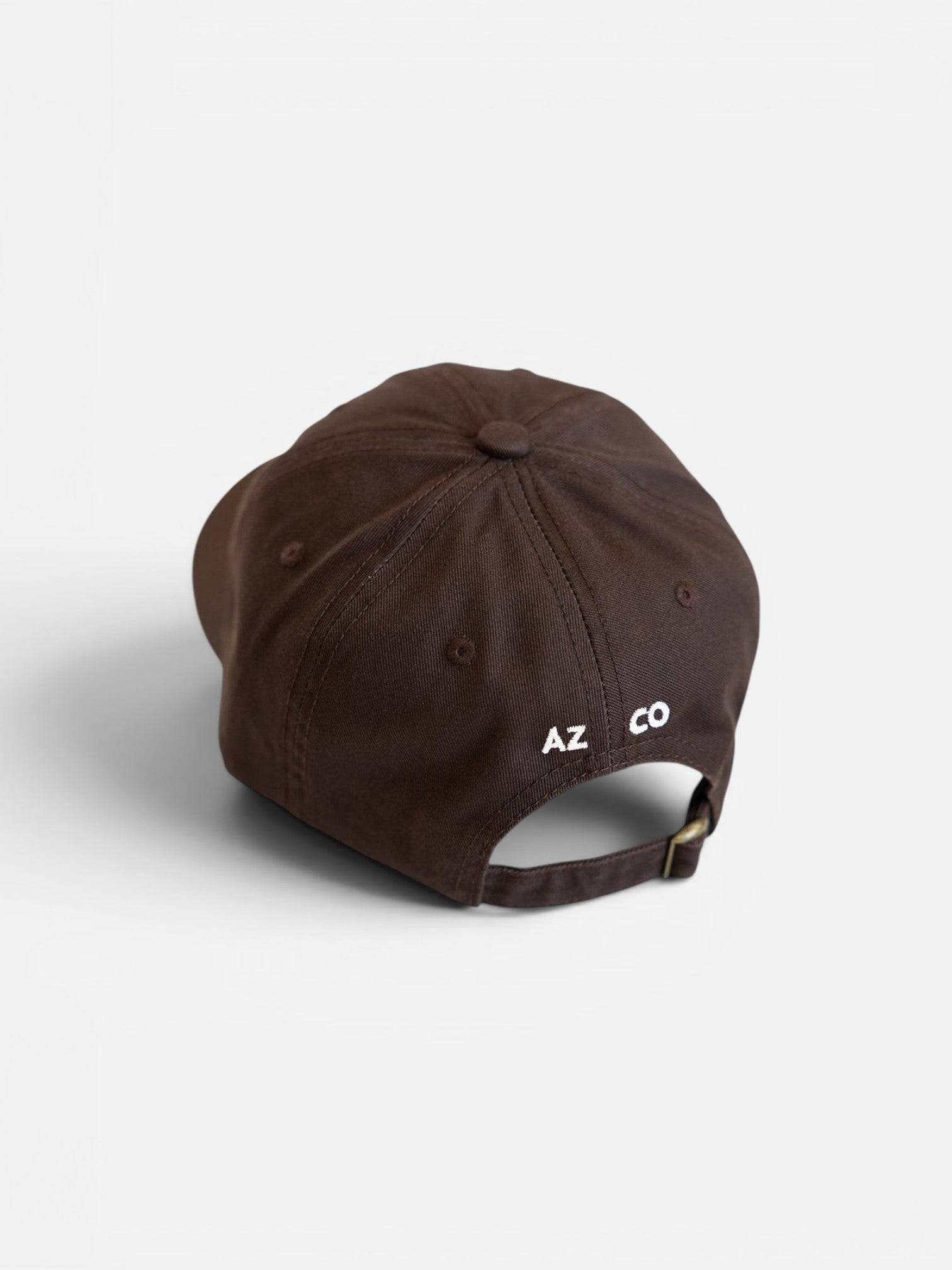 JONES + CO brown baseball cap with white embroidered logo on the back and adjustable metal strap closure