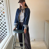 Woman wearing a brown JONES + CO baseball cap with white lettering, styled with a denim shirt and brown trousers.