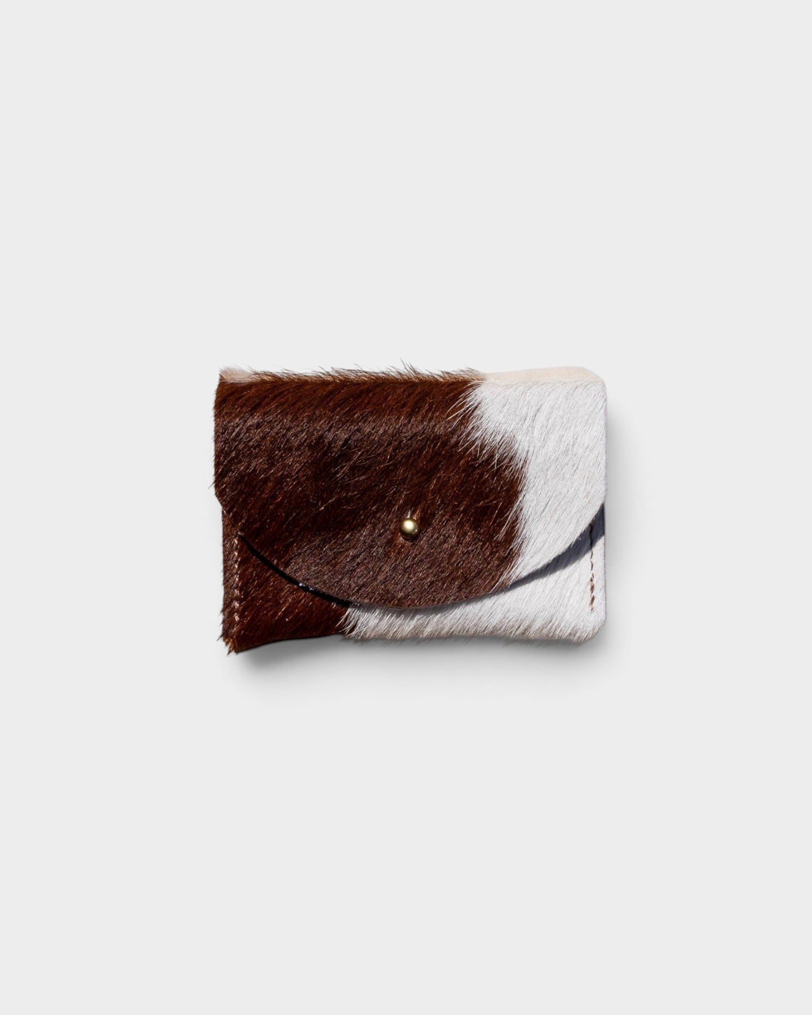 JONES + CO brown and white cowhide cardholder with a solid brass fastener, perfect for cards and cash.