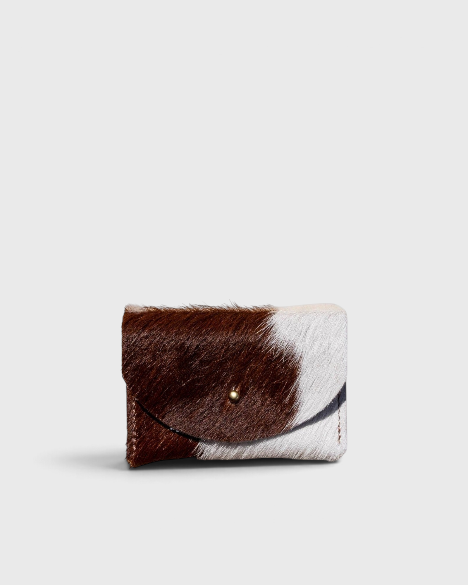 JONES + CO brown and white cowhide cardholder with a solid brass fastener, perfect for cards and cash.