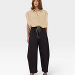 JONES + CO Cali Shirt in Sahara beige, a sleeveless collared button-up with cinched waist, paired with black wide-leg pants.