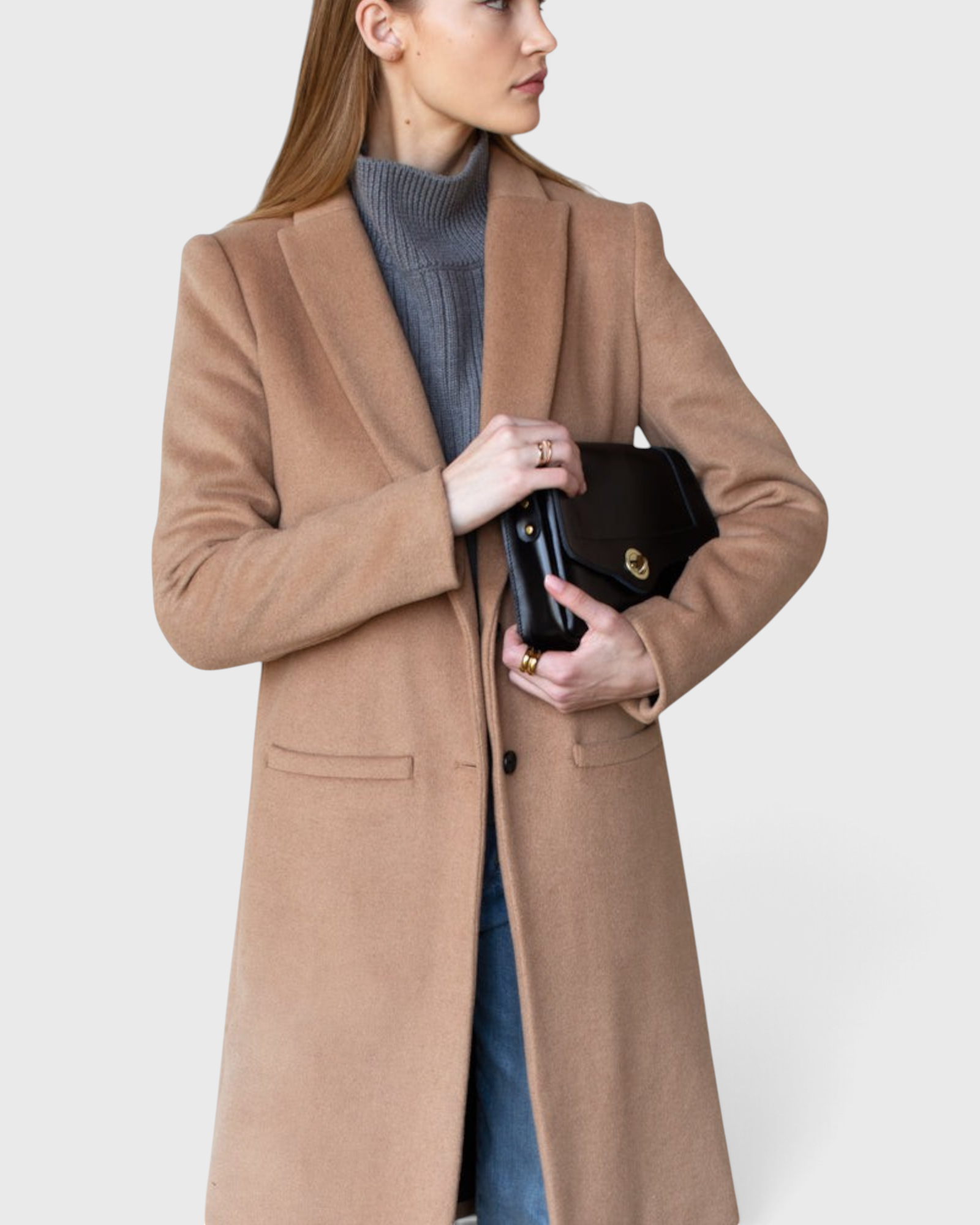 JONES + CO camel wool cashmere tailored coat with notch collar worn over a grey turtleneck and blue denim jeans.