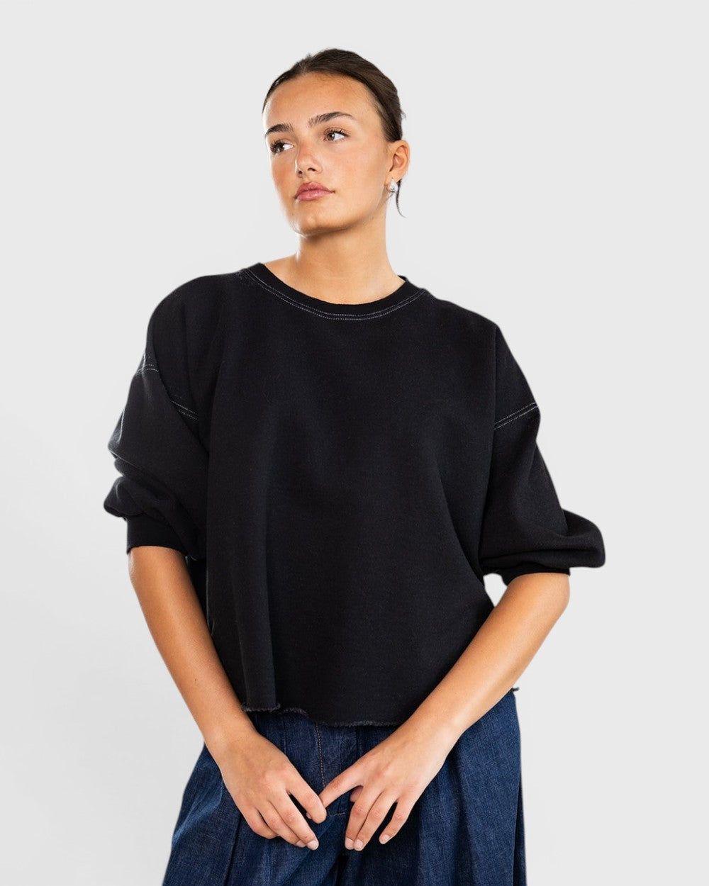 Model wearing a charcoal JONES + CO Rachel Comey Fond sweatshirt with drop shoulders and raw edge hemline