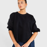 Model wearing a charcoal JONES + CO Rachel Comey Fond sweatshirt with drop shoulders and raw edge hemline