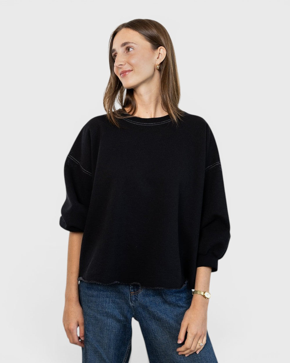 Model wearing a charcoal JONES + CO Fond sweatshirt with drop shoulders, cropped sleeves, and a raw edge hemline.