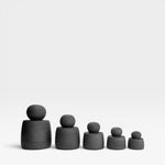 JONES + CO matte charcoal stoneware stash jars with chunky knobs, displayed in graduated sizes.