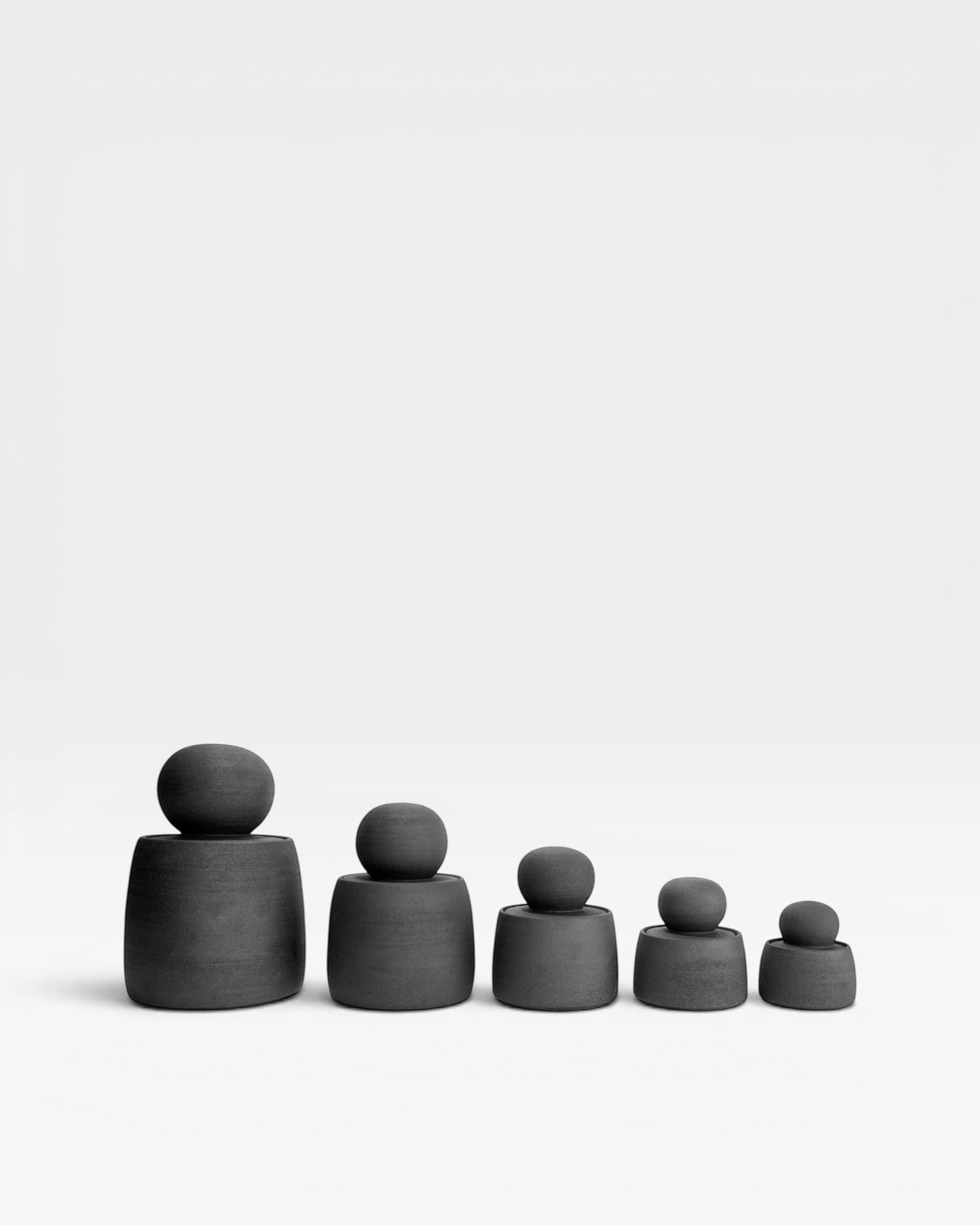 JONES + CO matte charcoal stoneware stash jars with chunky knobs, displayed in graduated sizes.