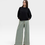 JONES + CO charcoal crewneck sweatshirt with drop shoulders, raw edge hem, and distressing. Model wears wide-leg jeans.