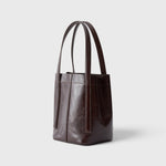 JONES + CO Bucket Tool bag in chestnut lustre leather with vertical paneling, elongated handles, and open top design.