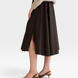 JONES + CO chocolate brown midi skirt with side slits and pockets, paired with a beige sweater and brown heels.