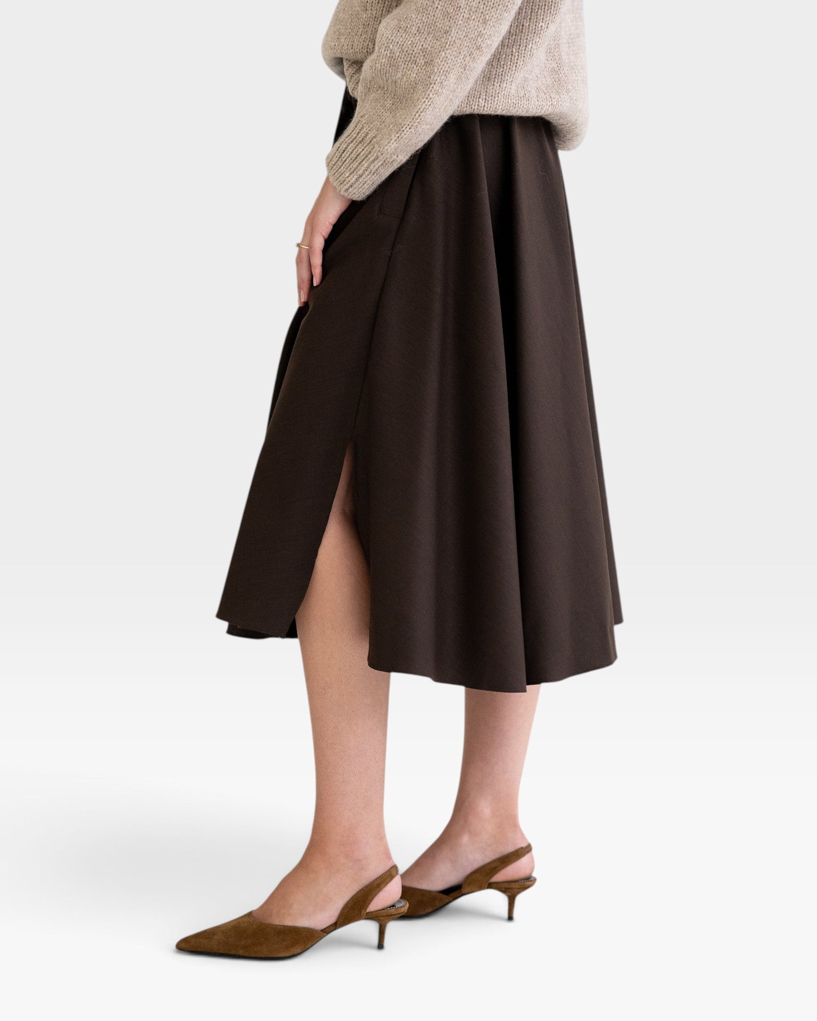 JONES + CO chocolate brown midi skirt with side slits and pockets, paired with a beige sweater and brown heels.