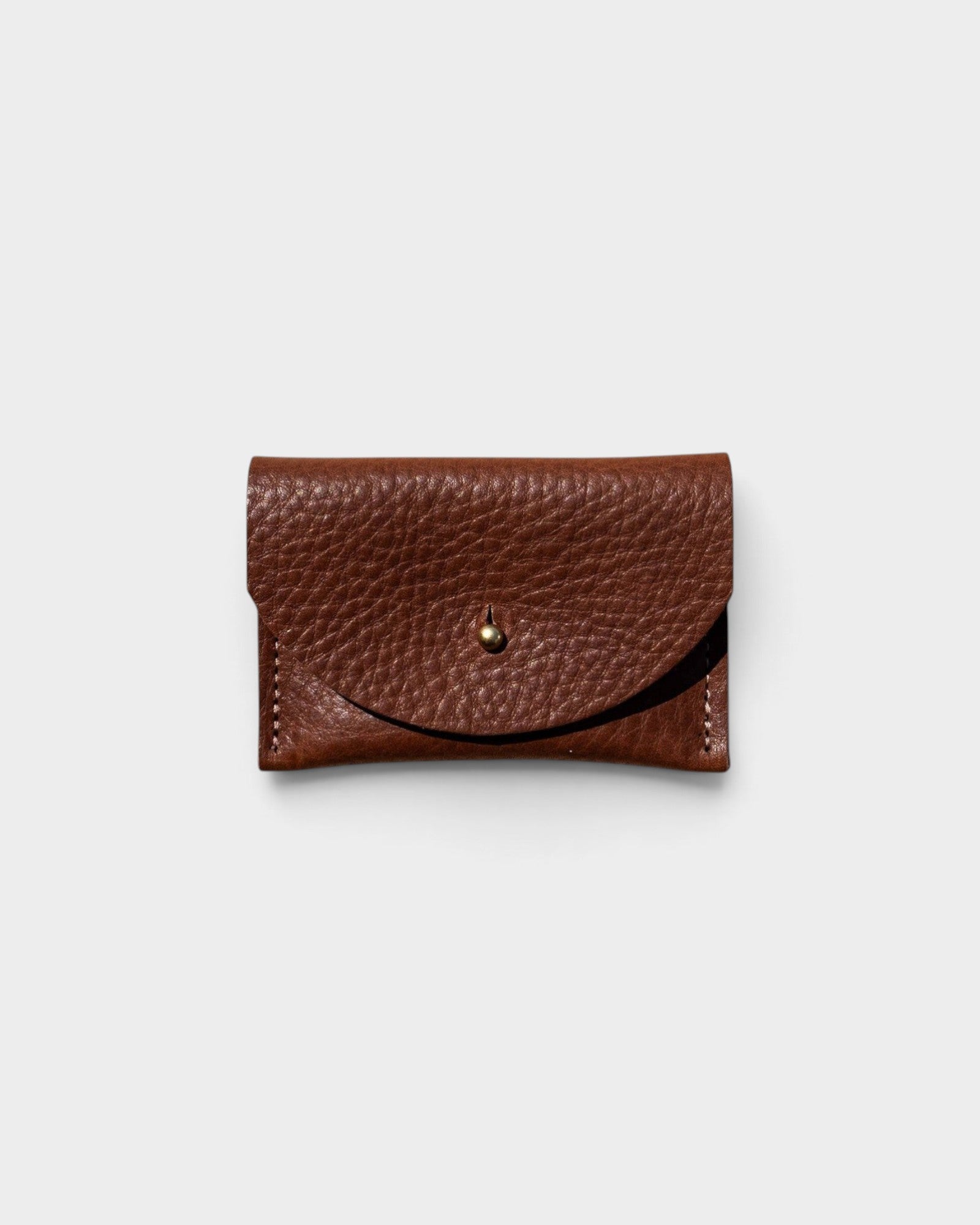JONES + CO chocolate brown pebbled leather cardholder with a solid brass fastener, front view.