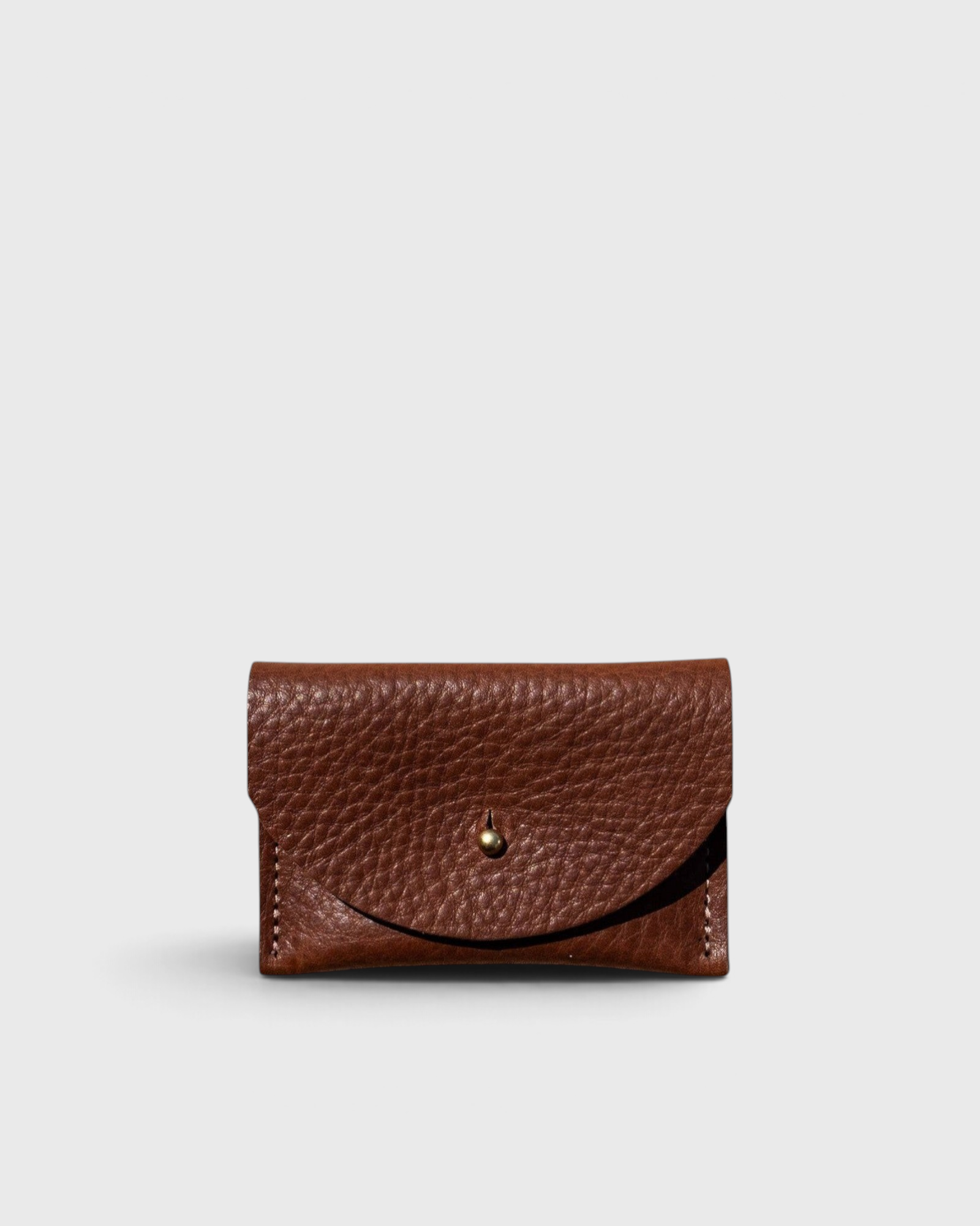 JONES + CO chocolate brown pebbled leather cardholder with a solid brass fastener, front view.