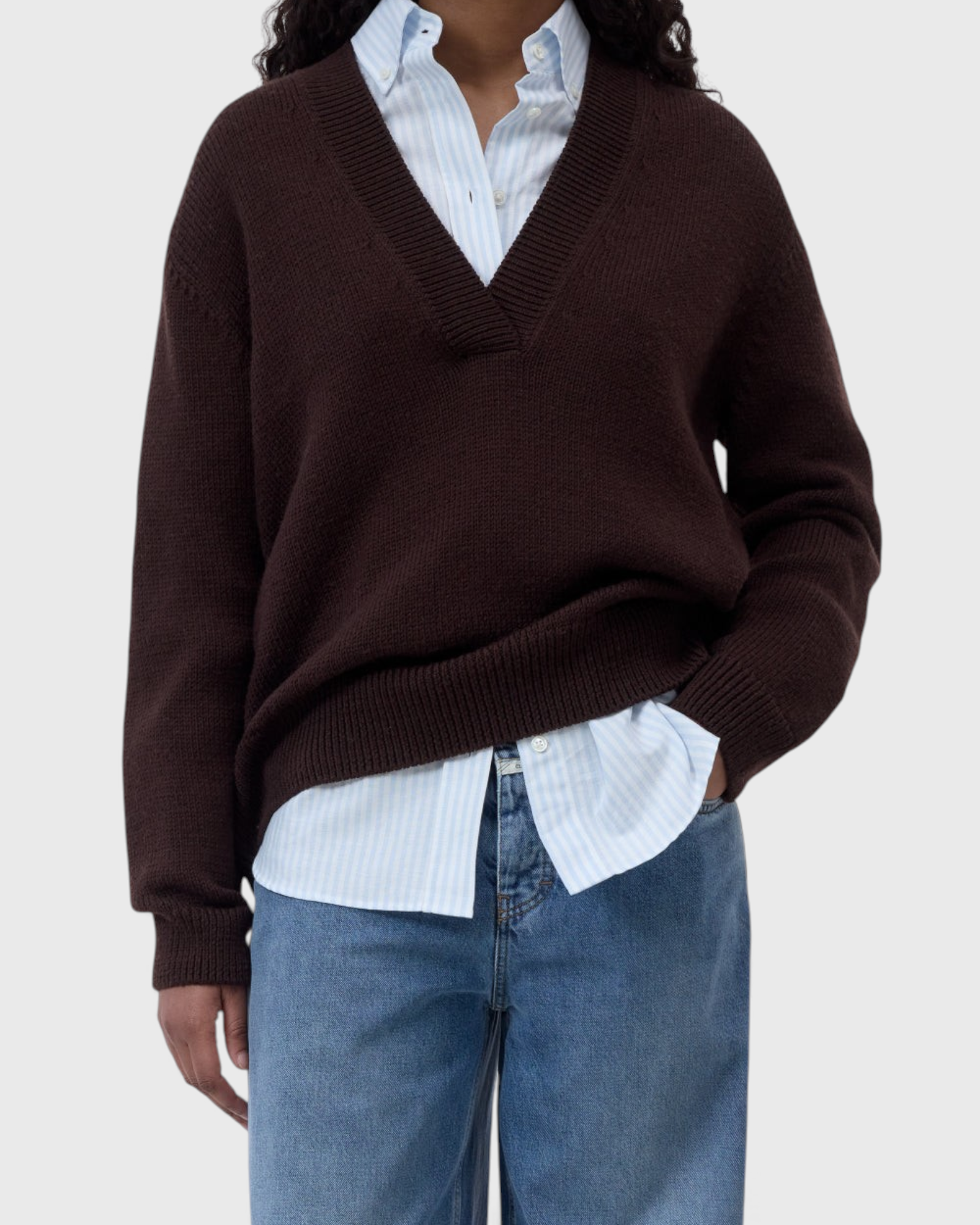 JONES + CO cinder brown wool-blend V-neck jumper with ribbed trims worn over a light blue striped shirt and jeans.