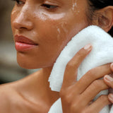JONES + CO cleansing balm on a woman's face, being wiped with a white towel. Hydrated skin.
