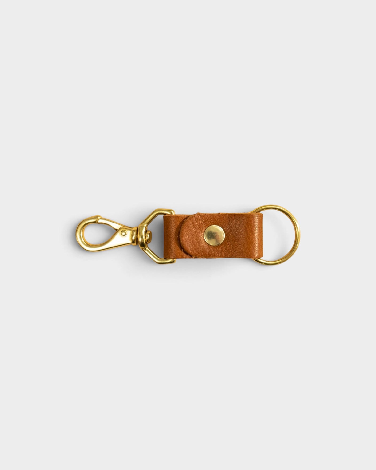 JONES + CO cognac leather keychain with gold-tone metal clasp and ring on a light grey background