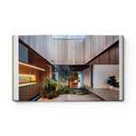 Open pages of JONES + CO Courtyard Homes book showing a modern residence with a central indoor garden and wood walls.