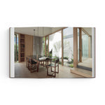 JONES + CO Courtyard Homes book open to a spread showing a modern dining room with floor-to-ceiling windows and garden.